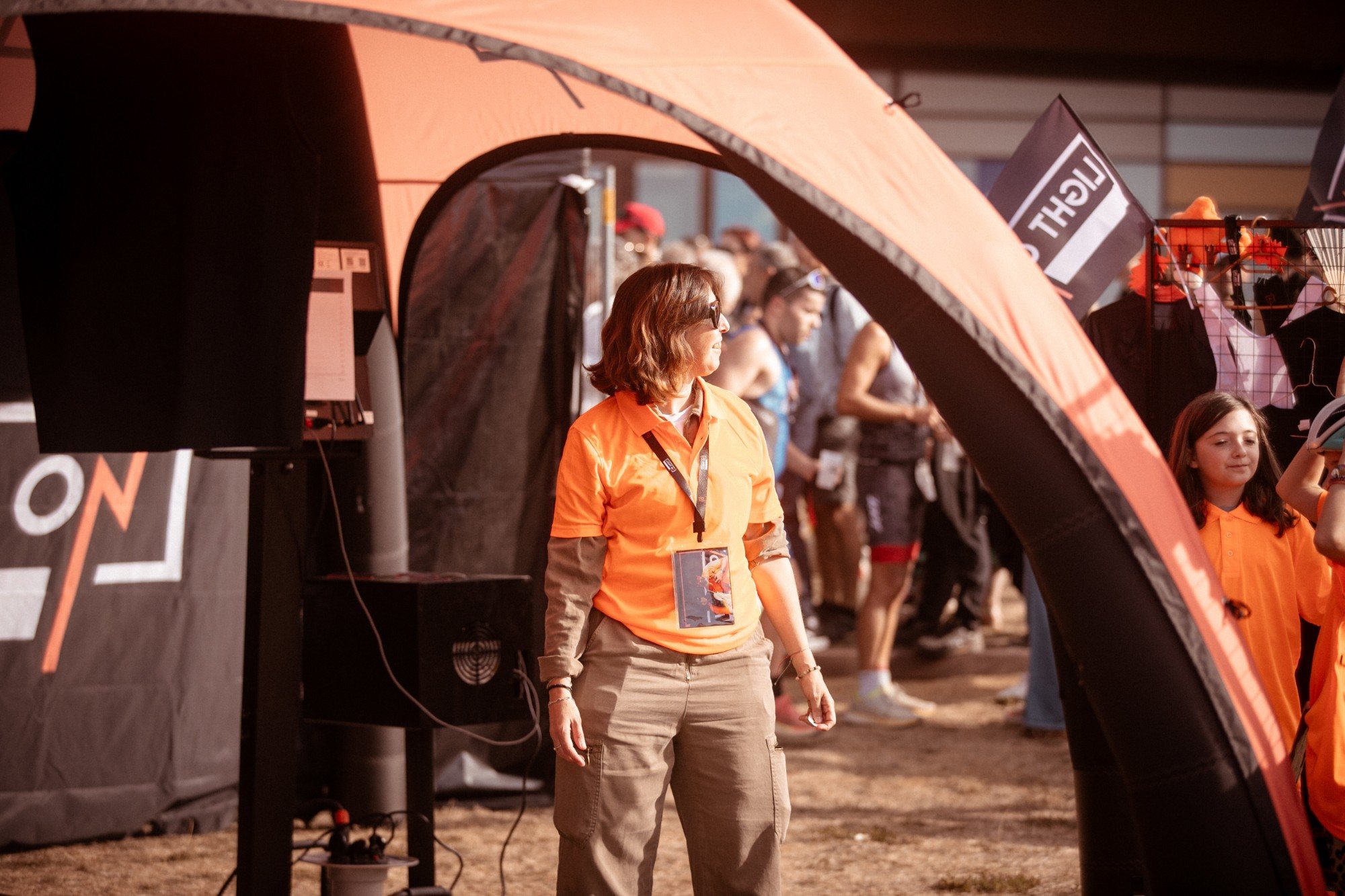 Bénévole du LIGHT ON Crew en polo orange au Village LIGHT ON