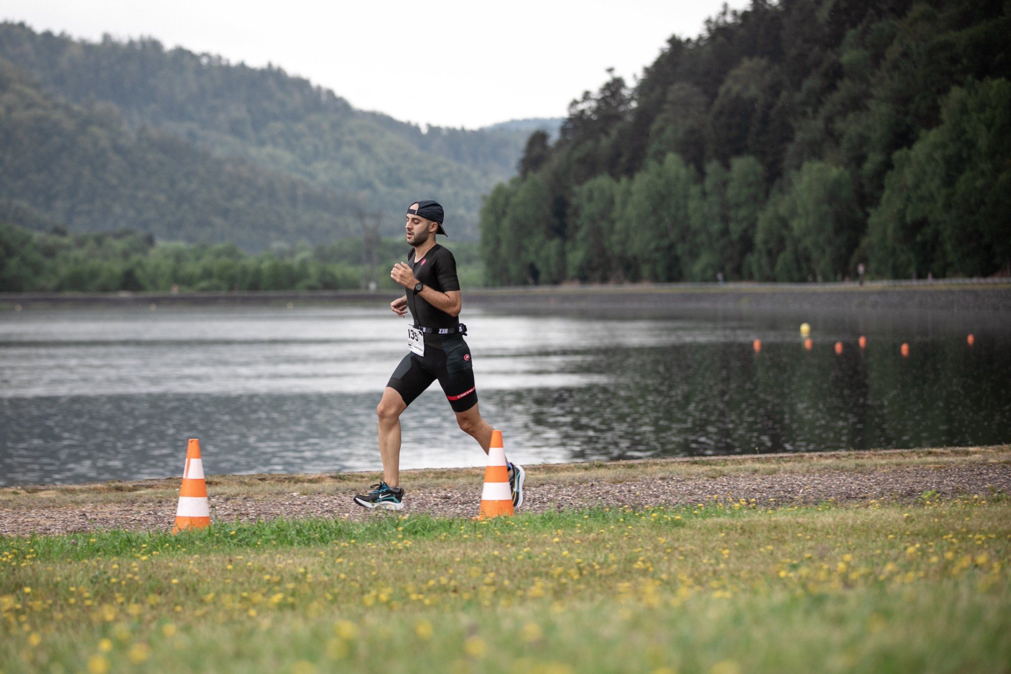 Triathlète en course à pied au bord du lac, forêt et collines en arrière-plan, à Pierre-Percée