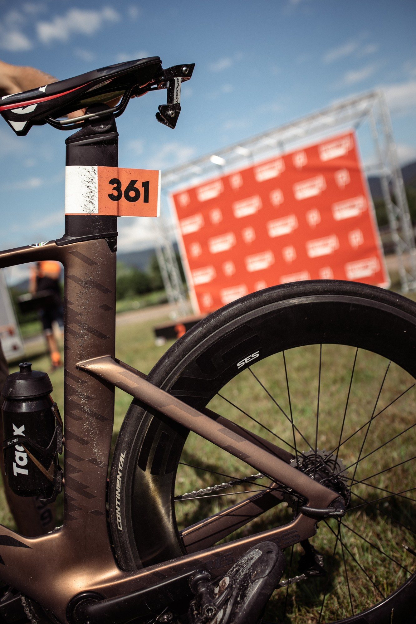 Vélo de triathlon avec son numéro sur la tige de selle, devant le mur LIGHT ON TRI