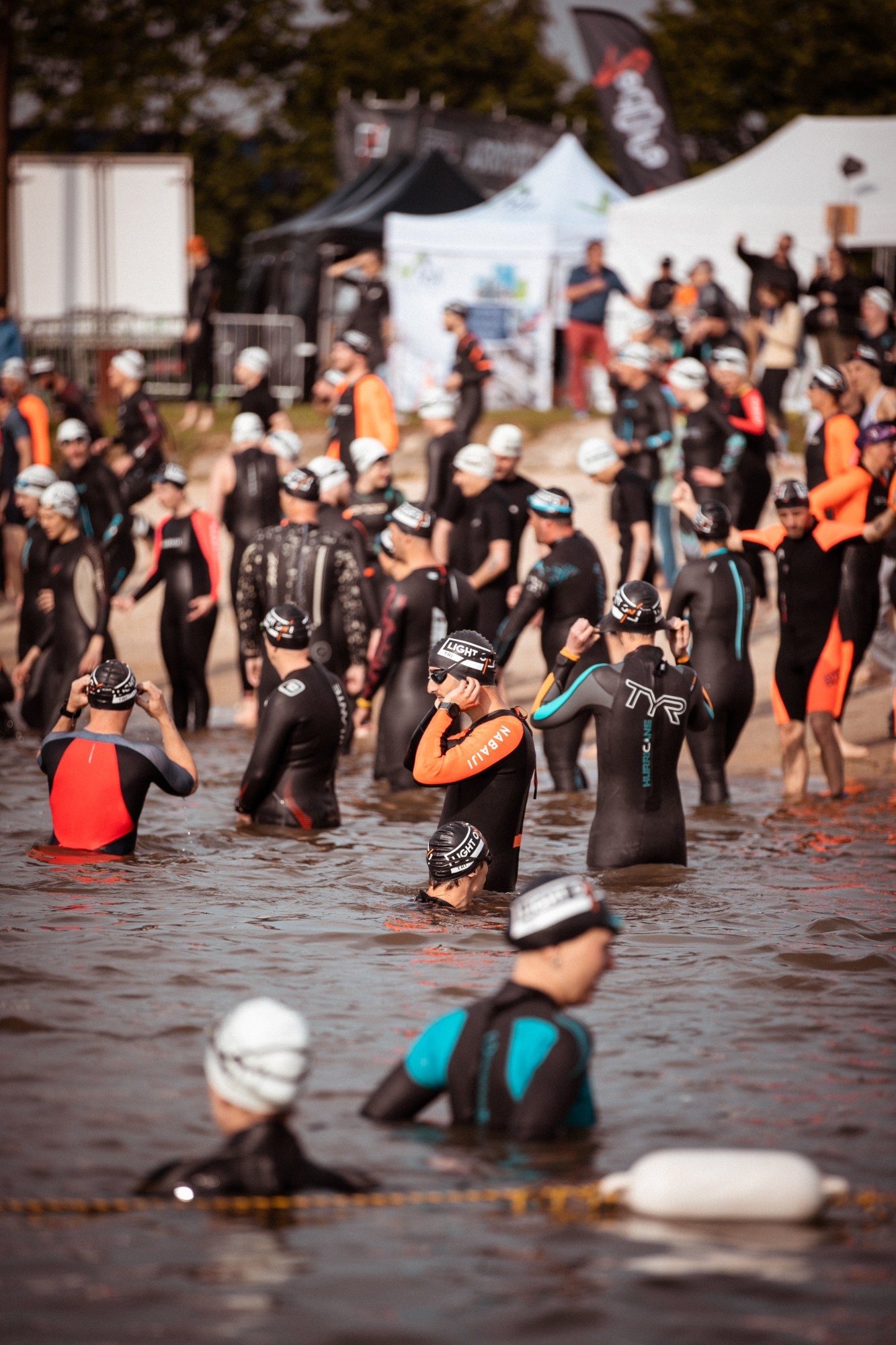 Triathlètes en combinaison qui ajustent leur bonnet LIGHT ON avant le départ natation à Woippy